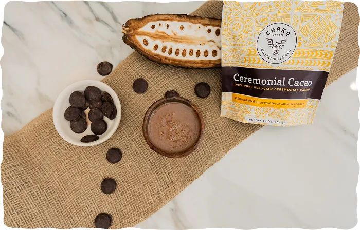 Bag of Chaka Peruvian ceremonial cacao with cacao discs, a halved cacao pod and a cup of cacao