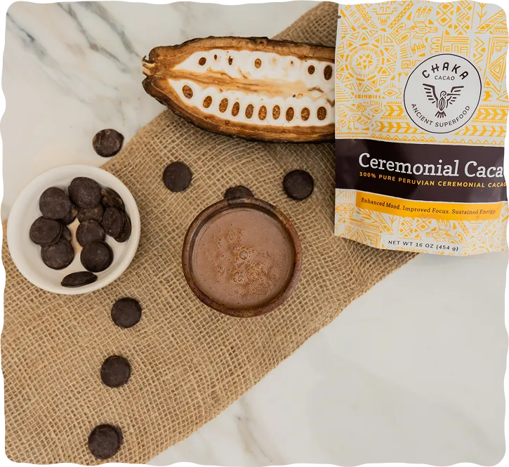 Cup of ceremonial cacao with a halved cacao pod, cacao discs and a bag of Chaka Peruvian ceremonial cacao