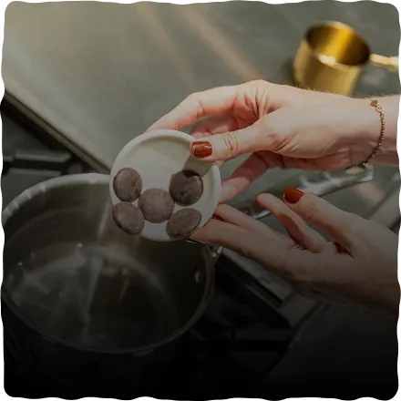 Adding Chaka cacao discs to warm water in a saucepan